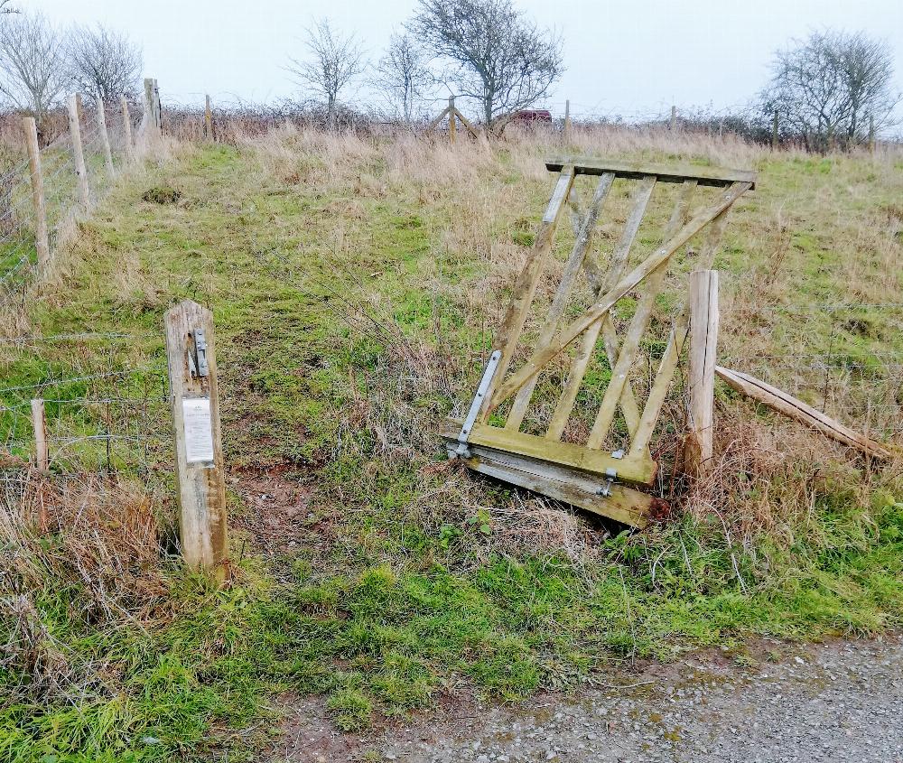A photo of a gate in a field completely broken